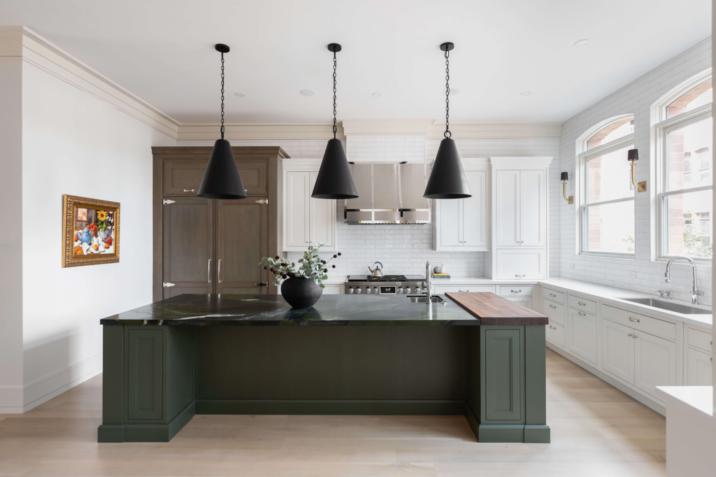 Luxurious kitchen with dark green island, white cabinetry, integrated appliances, and large arched windows.